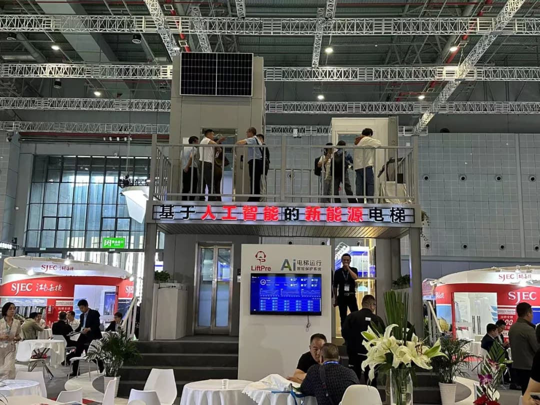 SJEC exhibition stand at the World Elevator & Escalator Expo 2024 in Shanghai, with a two-storey elevator display carrying a roof-mounted solar panel and a LiftPre monitoring screen below