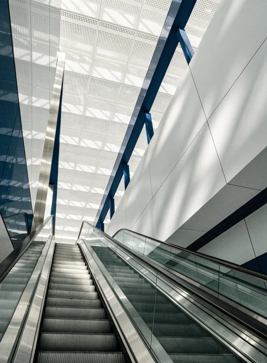 Modern escalators with brushed stainless balustrades rising through a bright contemporary atrium