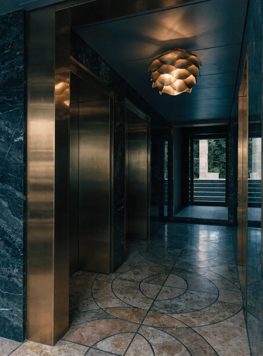 Luxury hotel elevator lobby with bronze-toned door frames against dark marble