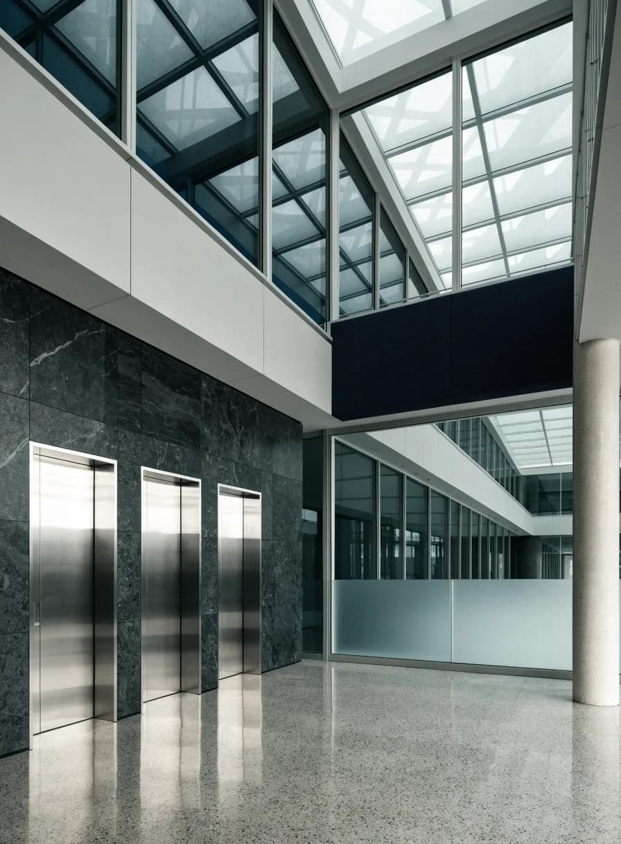Corporate office tower lobby with a bank of stainless steel elevators and a dark stone feature wall