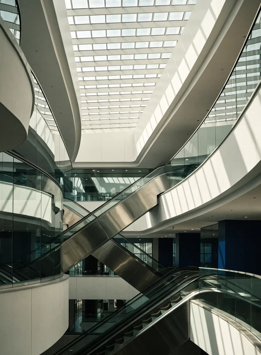 Shopping mall atrium with crossing escalators beneath a large skylight