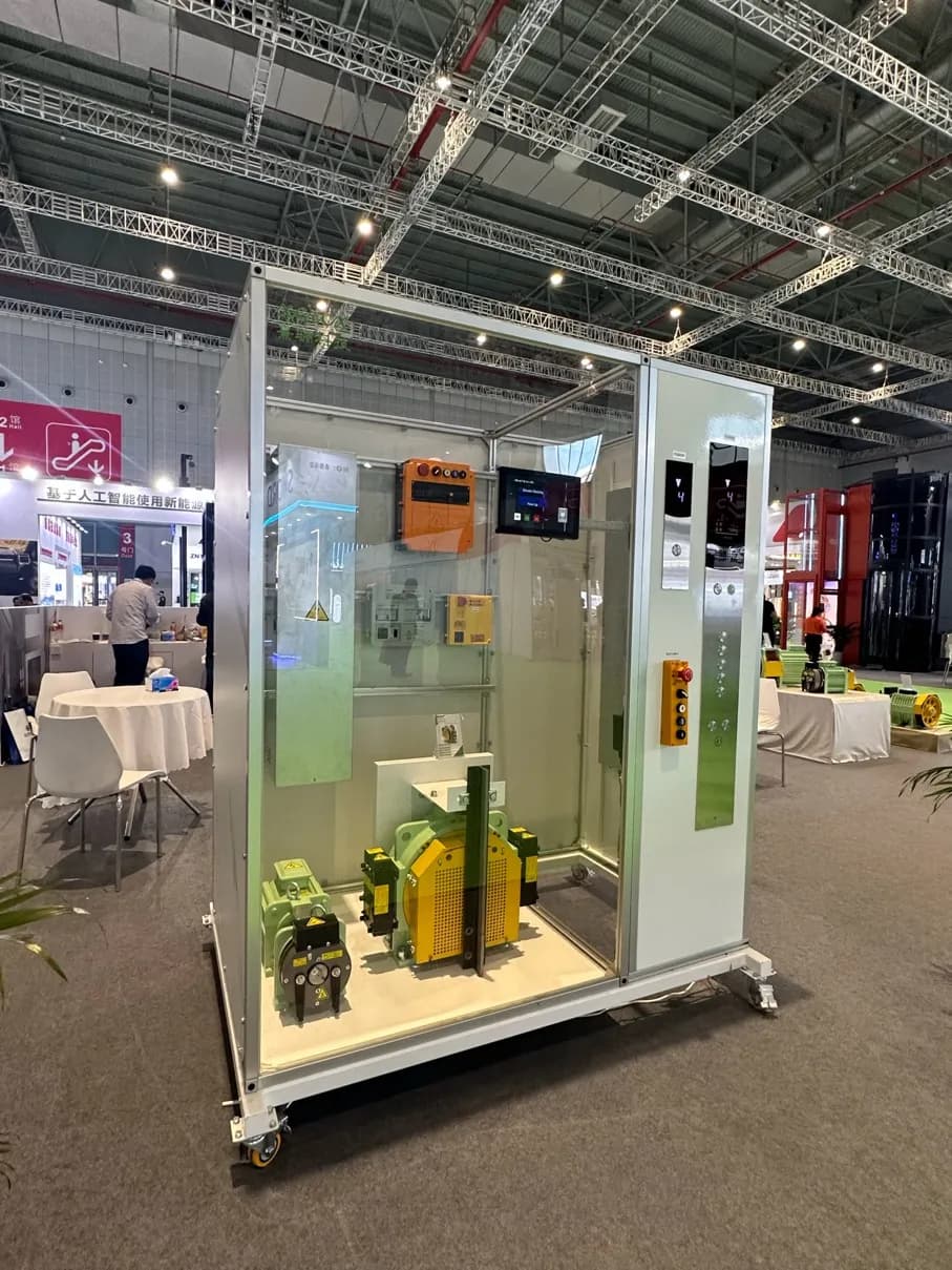 A home lift cabin beside an open controller board on the exhibition floor