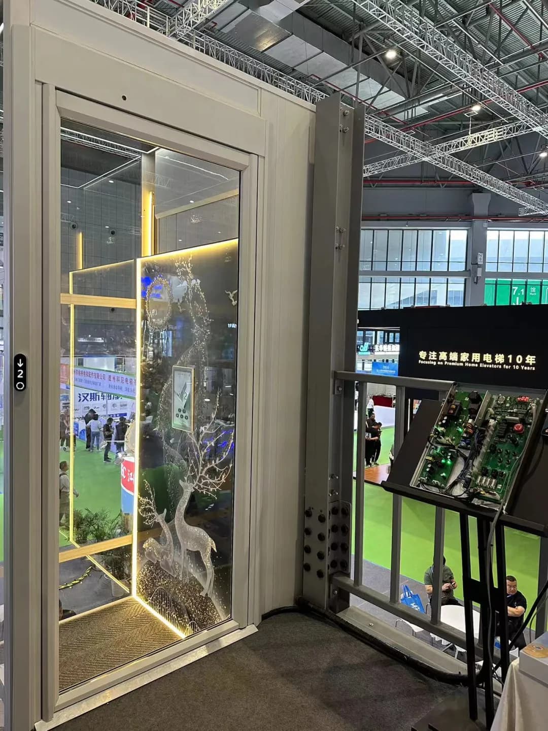 A glazed home lift on the SJEC stand, its cabin lit and dressed as a domestic interior