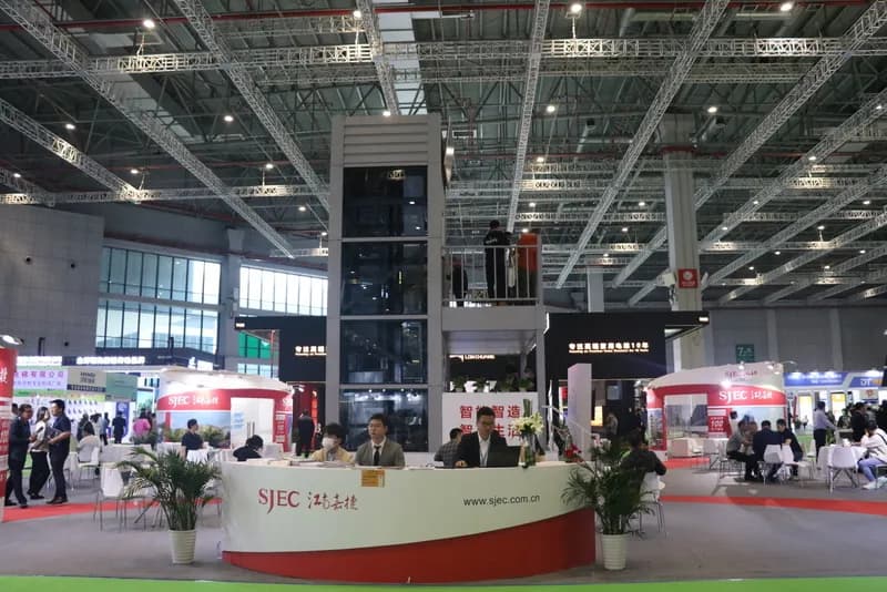 The SJEC reception desk at the exhibition, with the demonstration elevator shaft rising behind it