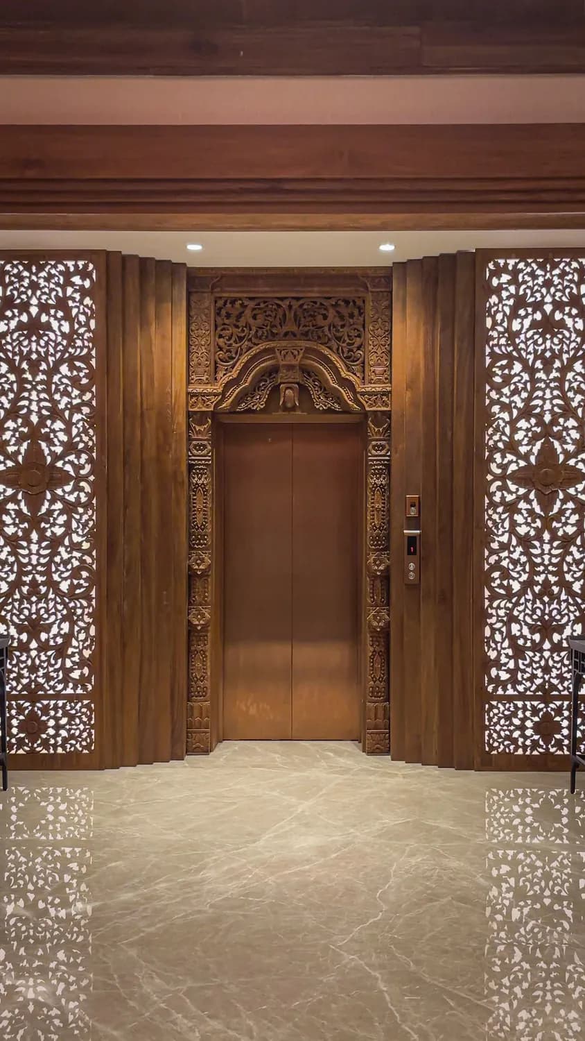 Home lift set into a carved timber surround with fretwork screens either side, at an art gallery in Green BSD