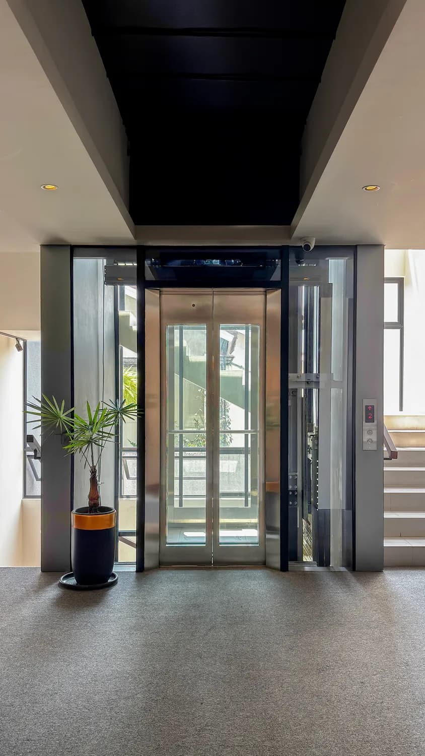Glazed home lift with a mirrored car standing in the lobby of House of Manna, South Jakarta