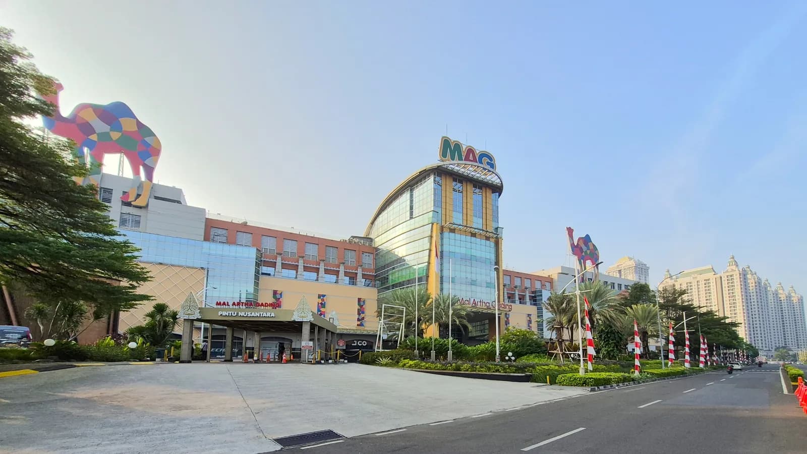 Street view of Mal Artha Gading in Jakarta, with the mall's glazed entrance rotunda and forecourt