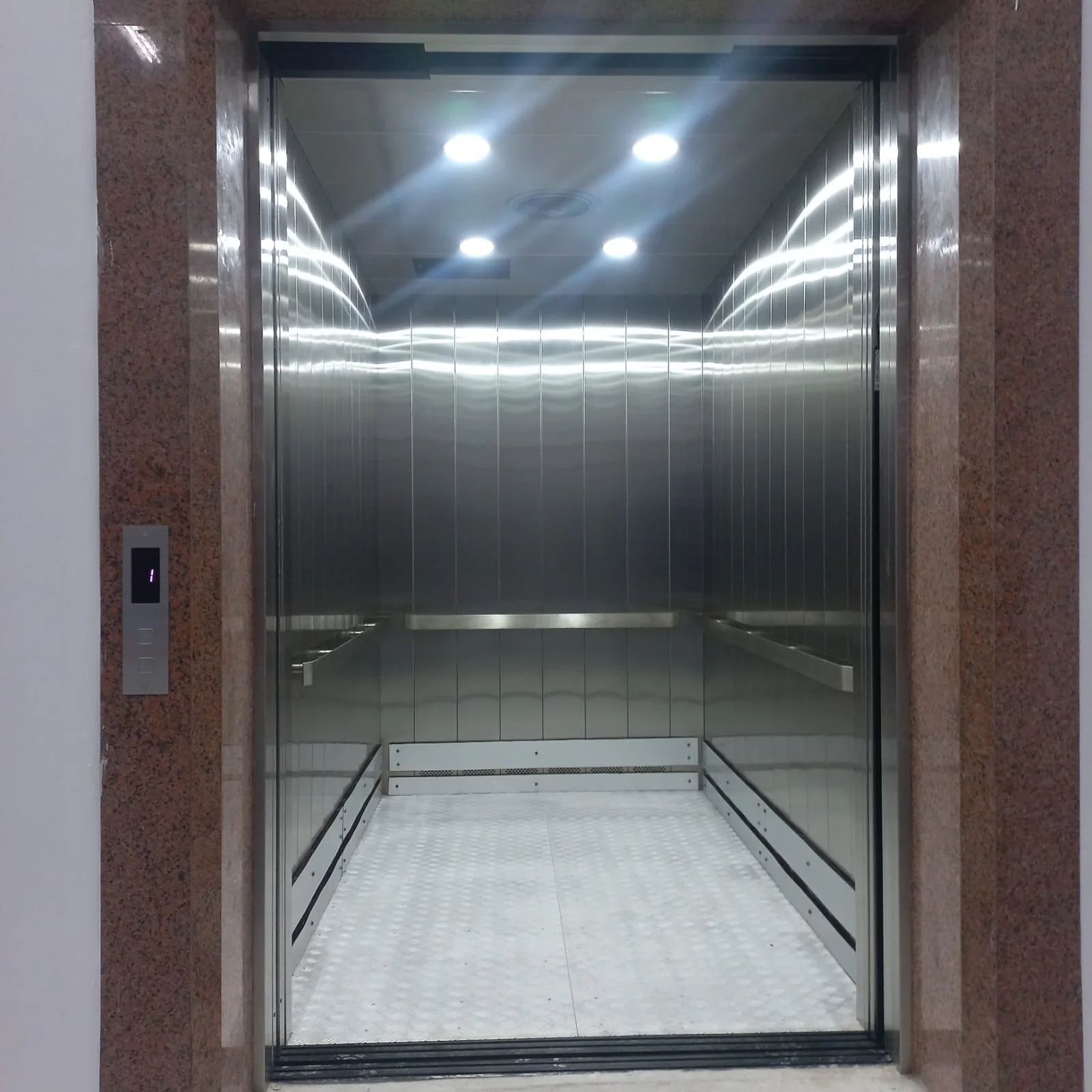 Stainless steel cargo lift car at the Synex warehouse, with bumper rails and a chequer-plate floor