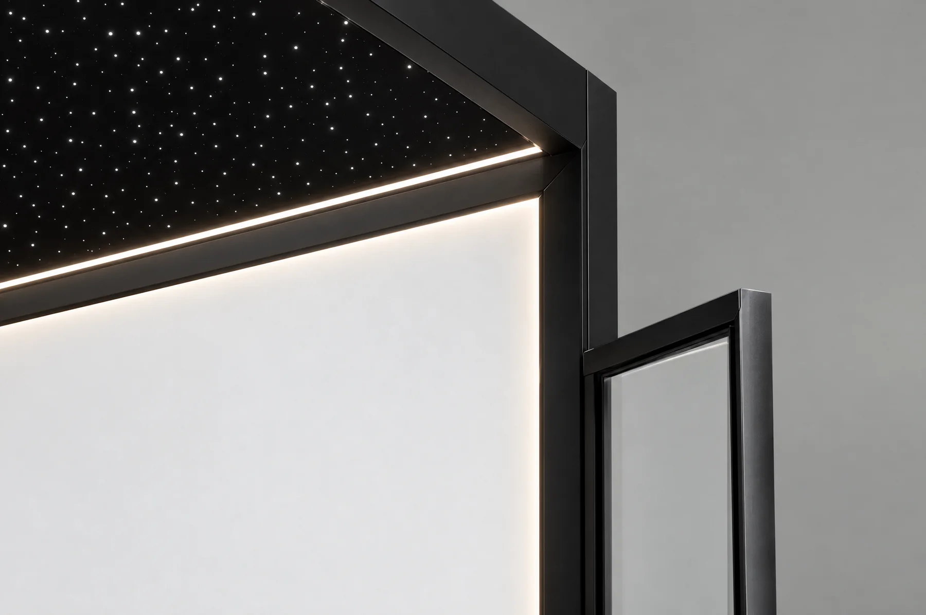 Close-up studio kabin Tenkai Tsuki: plafon bintang hitam di atas strip LED hangat, panel kabin putih yang menyala, dan rangka hitam pintu ayun kaca